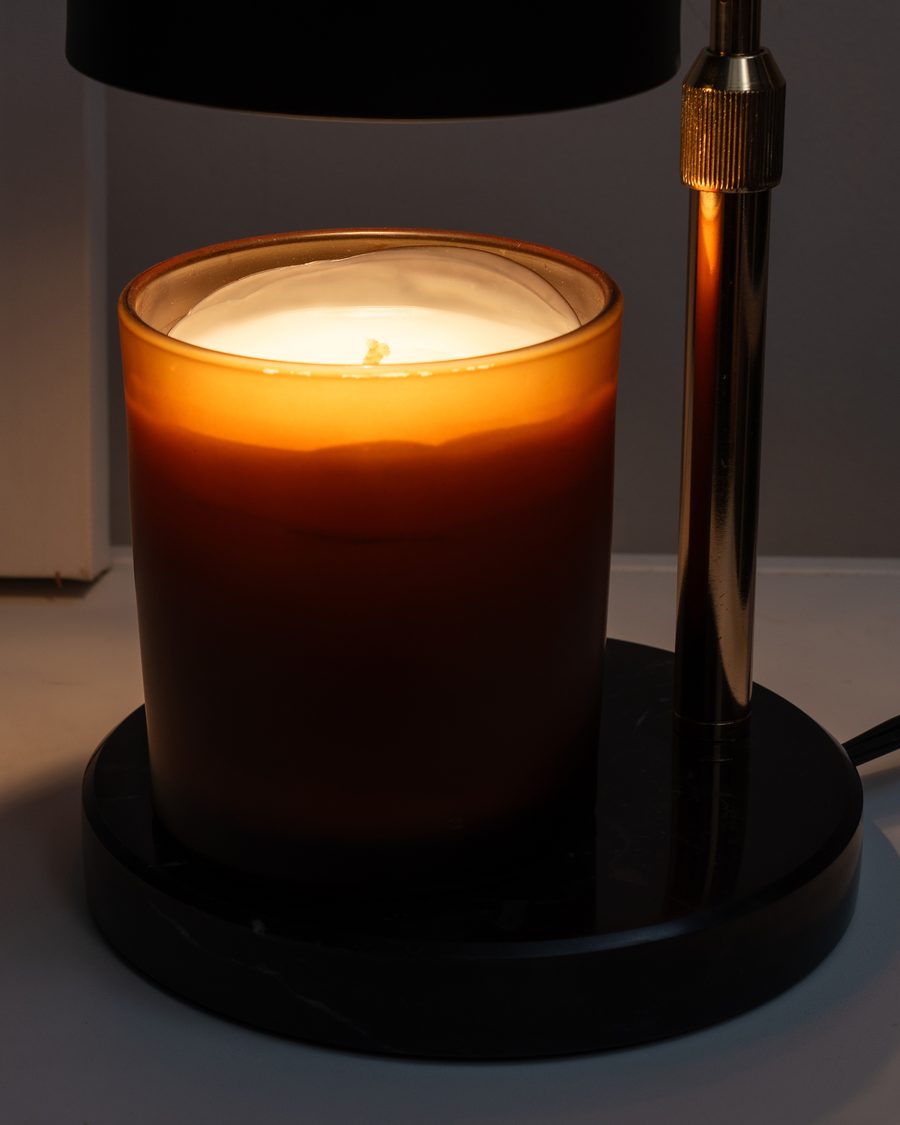 Candle wax melting evenly under the warmth of the lamp